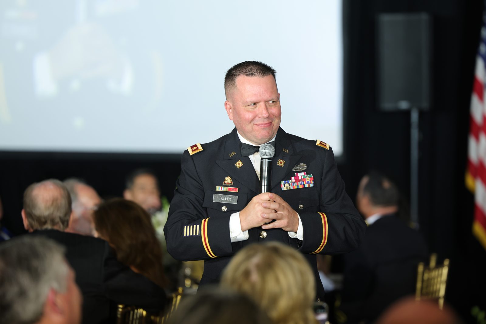Jody Fuller in U.S. Army dress blues holding a microphone and smiling at guests during the AUSA Greater Los Angeles Chapter Annual Ball