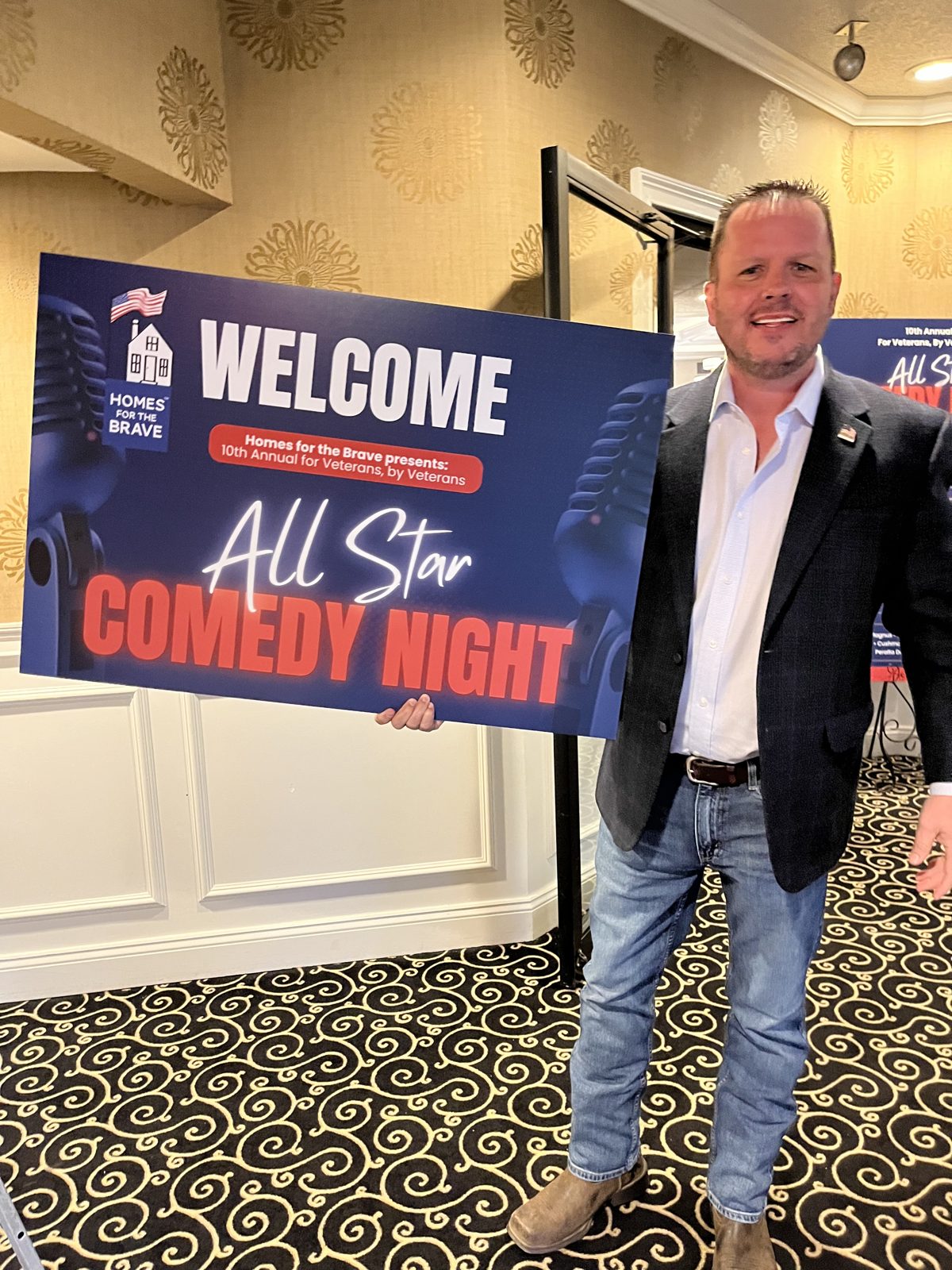 Jody Fuller holding the Homes for the Brave 10th Annual For Veterans, By Veterans All Star Comedy Night welcome sign